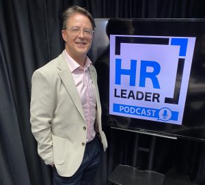 Craig Aunger standing next to a sign saying HR Leader podcast